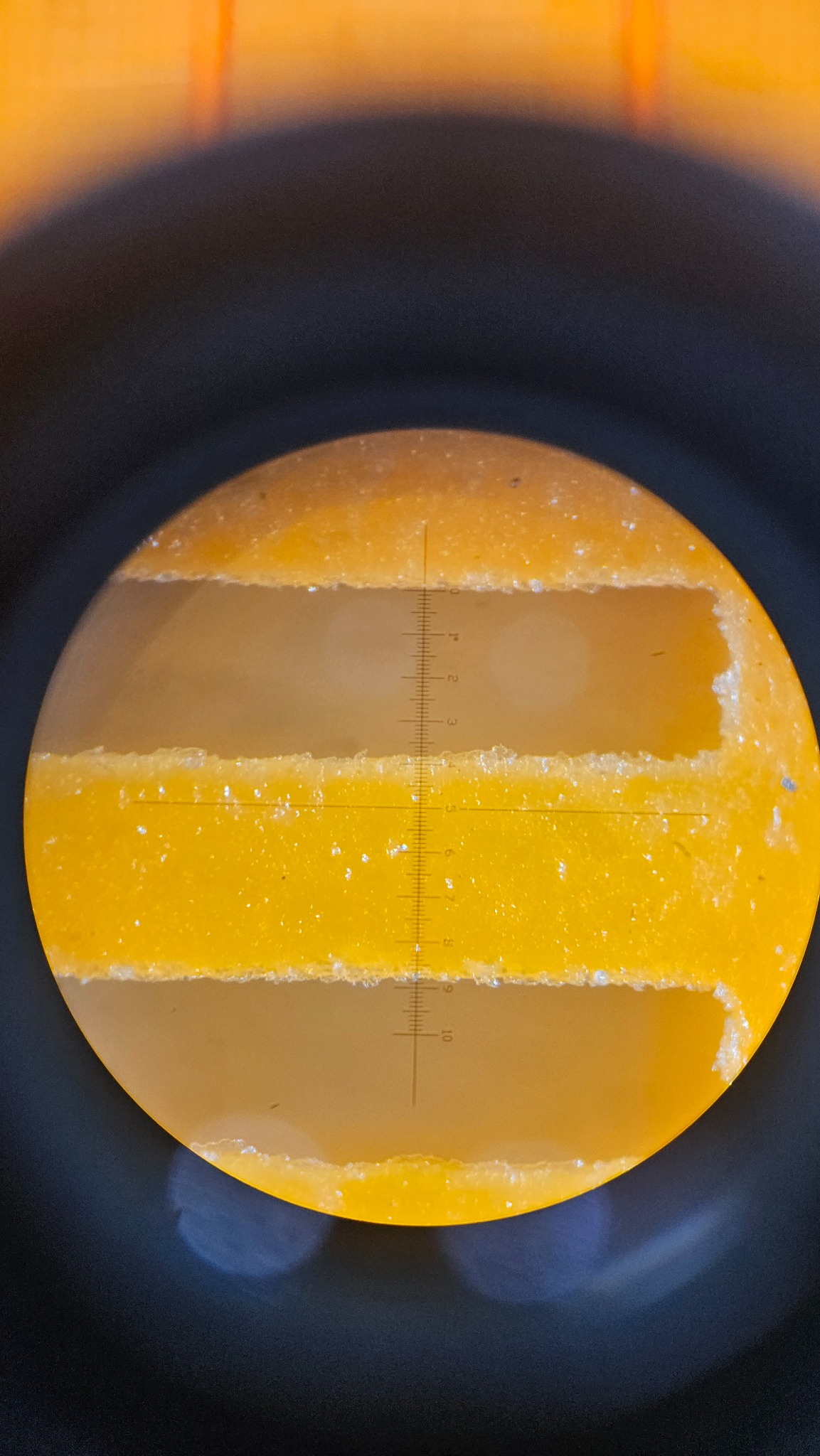 Polyurethane fine screen slot viewed through a microscope with a scale reticle
