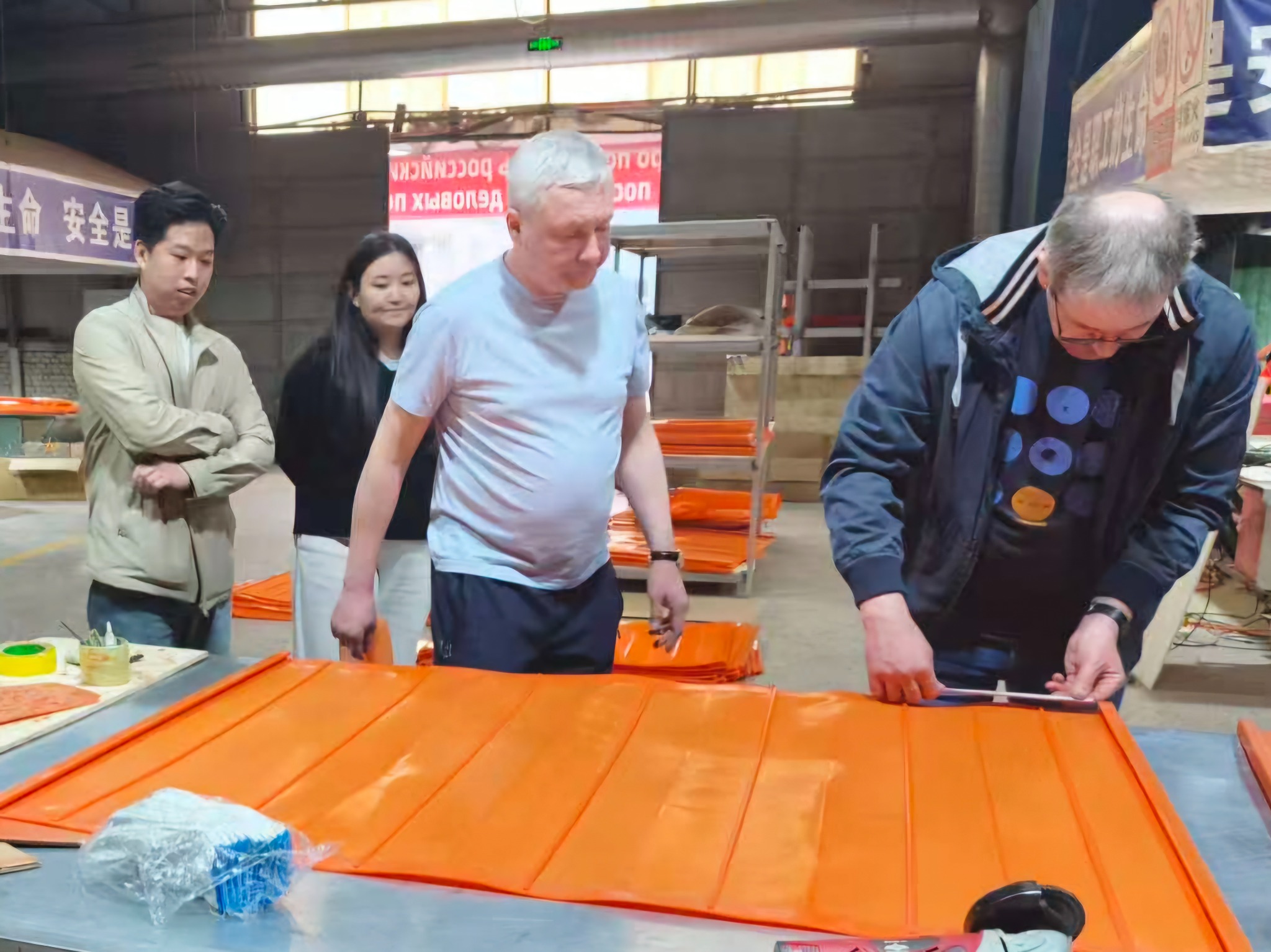 Russian customers view a polyurethane fine screen in the workshop and use a measuring tool to check an edge detail.